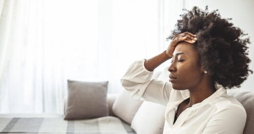 Lonely sad woman deep in thoughts sitting daydreaming or waiting for someone in the living room with a serious expression, she is pensive and suffering from insomnia sitting on couch