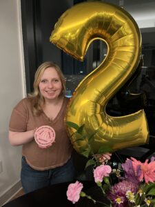 Photo of Katie posing with a big "2" balloon and a cookie designed like a 2-year sobriety chip.