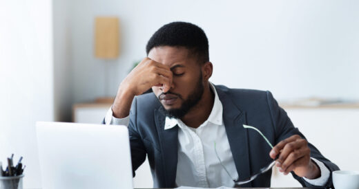 African businessman massaging his nose bridge, tired of long time work on laptop, copy space