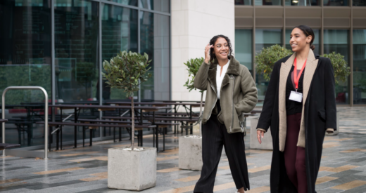 Two diverse women, 1 with a prosthetic leg, walking and talking together