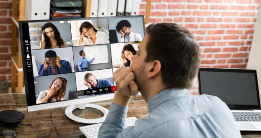 Man viewing a zoom screen on his computer of diverse employees looking exhausted