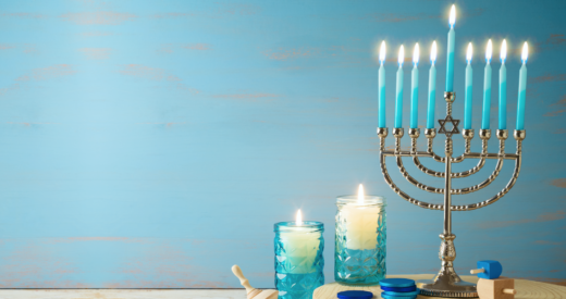 Jewish holiday Hanukkah concept with menorah, candles and dreidel on wooden table.