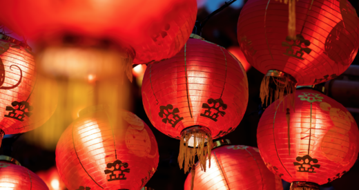 Rows of colorful glowing red Chinese lanterns hanging high across the street during Lunar New Year Celebrations.