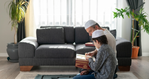 Son and father reading Quran together at home stock photo