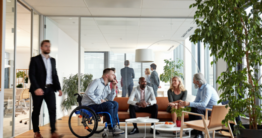 Business associates in 20s, 40s, and 50s relaxing and exchanging ideas in sitting area of modern office.