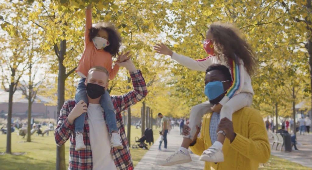 Image of family outside with children on the shoulders of parents