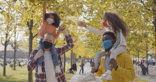 Image of family outside with children on the shoulders of parents