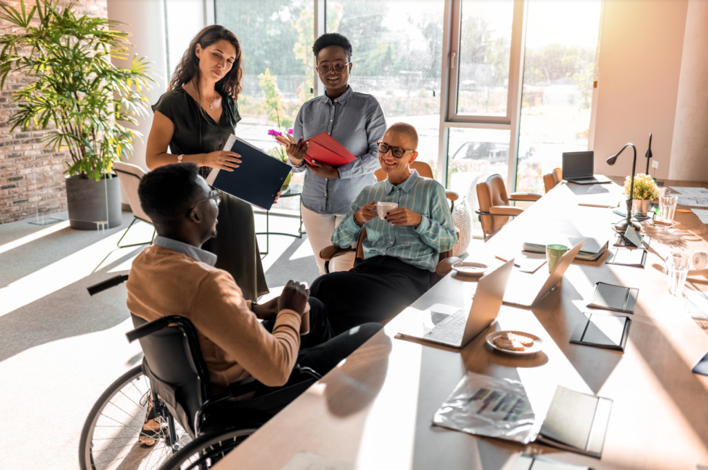 Diverse coworkers listening to a man in a wheelchair's idea