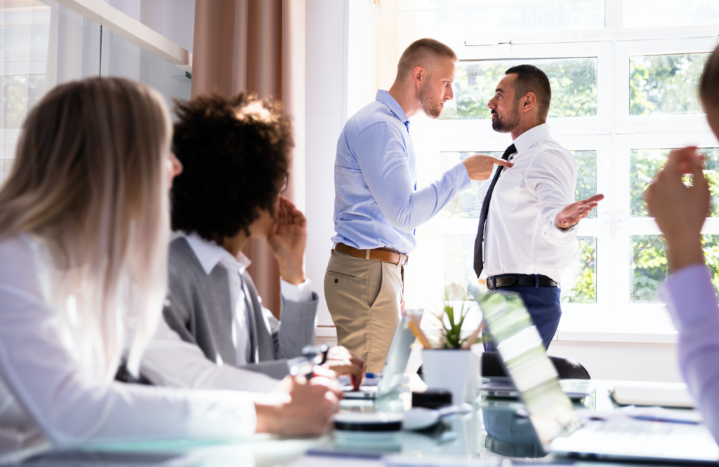 Stressed Businesspeople Sitting In Front Of Two Colleagues Fighting In Office