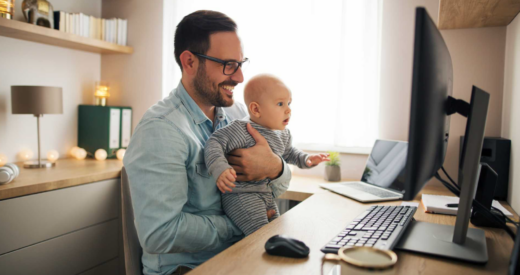 working dad holding baby while working stock image