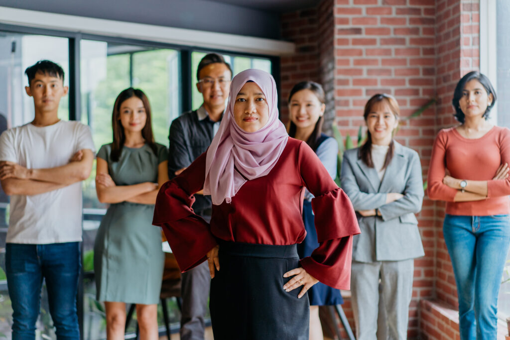 Image of confidence Muslim businesswoman and her colleagues. Professional Malaysian business team looking at camera.