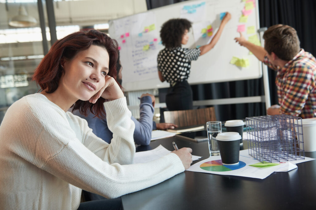 Shot of a young female designer looking thoughtful while sitting at a conference table with her colleagues