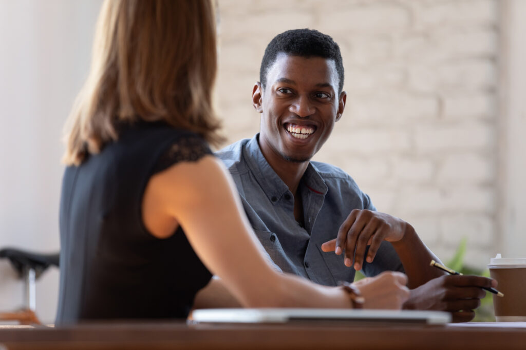 African manager listen to client preferences at business meeting, diverse teammates working together, mentor and intern talk. Job interview good first impression positive pleasant conversation concept