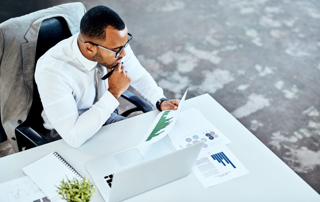 Cropped shot of a young businessman sitting in his office and looking contemplative while reading paperwork