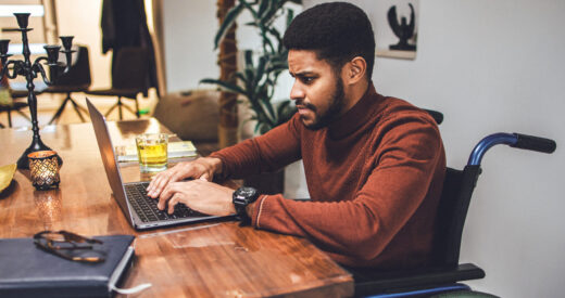 Disabled young African-American male meeting the deadline working at home using laptop.