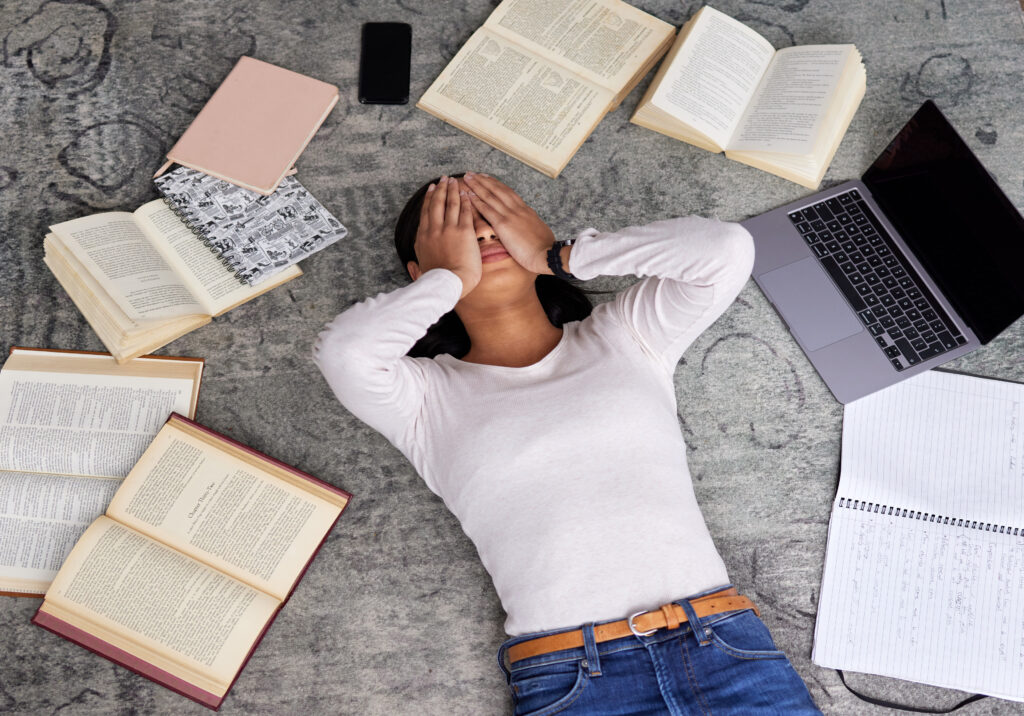 High angle shot of an unrecognizable young female student looking stressed while studying in the library