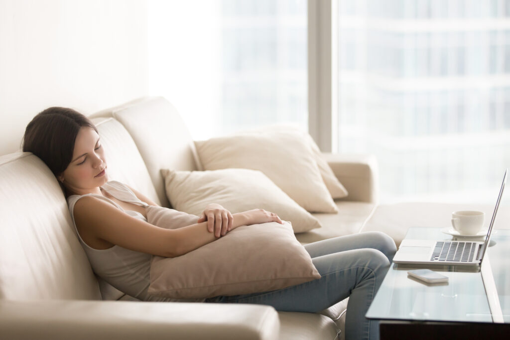 Young woman sleeping on couch in daytime, relaxing after computer work 