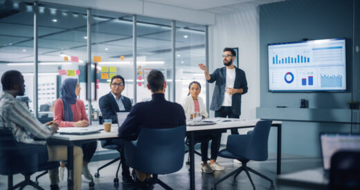 Diverse Modern Office: Businessman Leads Business Meeting with Managers, Talks, uses Presentation TV with DEI analytics, Infographics. Digital Entrepreneurs Work on e-Commerce Project.