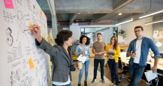 Latin American woman making a business presentation in a meeting at a creative office and pointing to her team her business plan