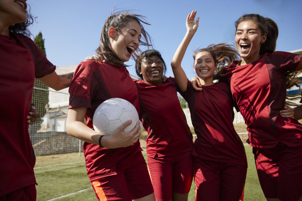 Group of multi-ethnic soccer players celebrating huddled in circle after winning match