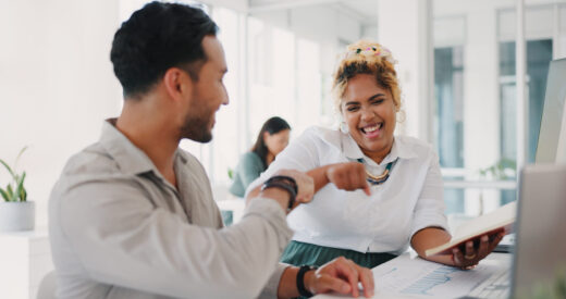 Laptop, success or happy employees fist bump in celebration of sales goals or target at office desk. Support, mission or woman celebrates partnership growth, team work or achievement with worker