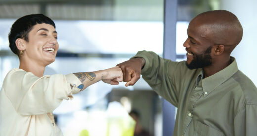 Two happy colleagues fist bumping