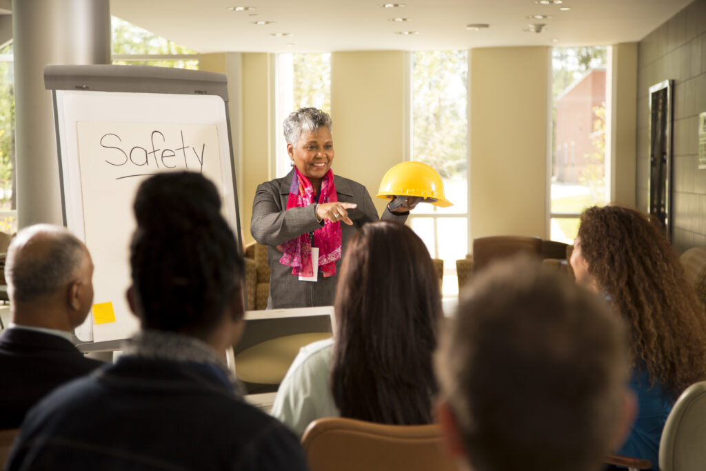 Business woman gives safety presentation at office. Multi-ethnic group of professionals.