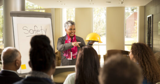 Business woman gives safety presentation at office. Multi-ethnic group of professionals.