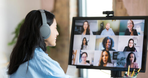 The mid adult female student wears her Bluetooth headphones as she joins the multi-ethnic group of students for a virtual college class.