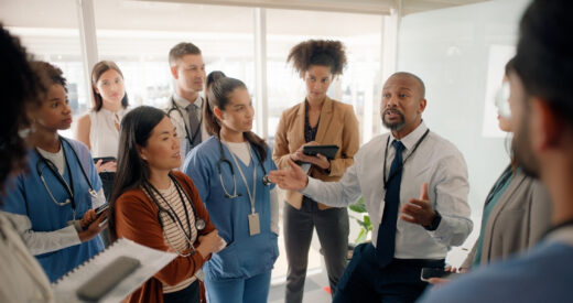 Boardroom, discussion and motivation for staff by executive in hospital for healthcare. Man, training and mentor of employees or nurses and tablets for notes of speech by leader in medical field