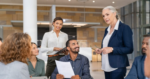 Group of mixed race business people discussing work in conference room. Senior business manager guiding employees in meeting. Group of businessman and businesswoman working together while brainstorming and sharing new ideas and strategy.