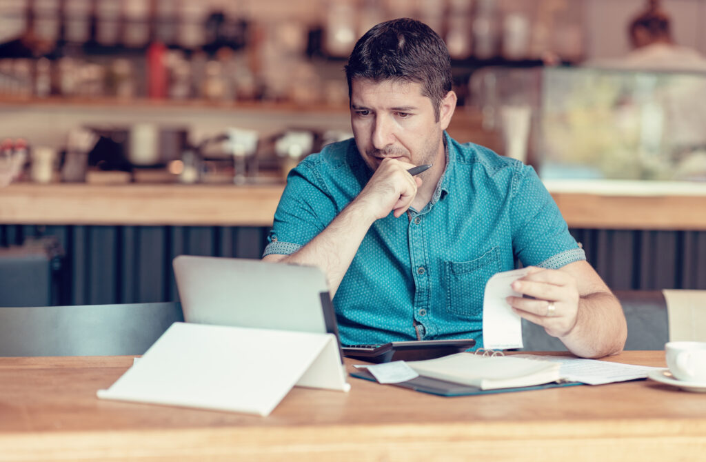 Restaurant owner checking monthly reports on a tablet, bills and expenses of his small business