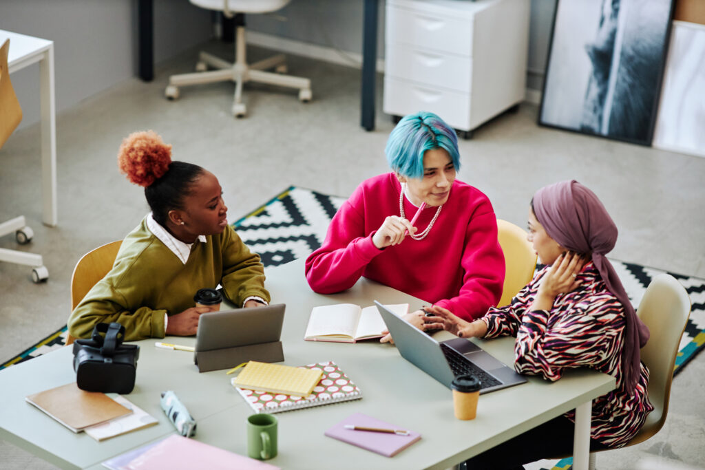 Diverse group of creative young people discussing project during meeting in office focus on Asian man with colored hair