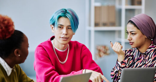 Portrait of young Asian man with colored hair talking to creative team in meeting