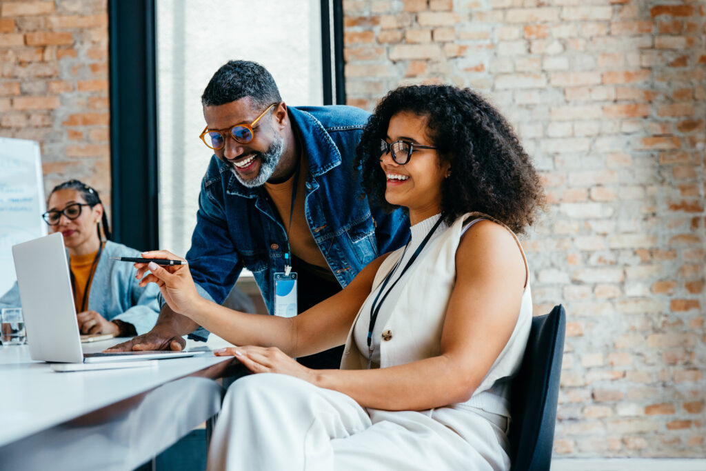 Senior and junior team members working together in an open office, highlighting teamwork, skill exchange, mentorship and professional collaboration in a creative environment.