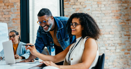 Senior and junior team members working together in an open office, highlighting teamwork, skill exchange, mentorship and professional collaboration in a creative environment.