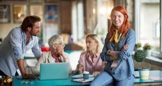 A young beautiful woman is posing for a photo while enjoying a work with her colleagues in a relaxed atmosphere in the office