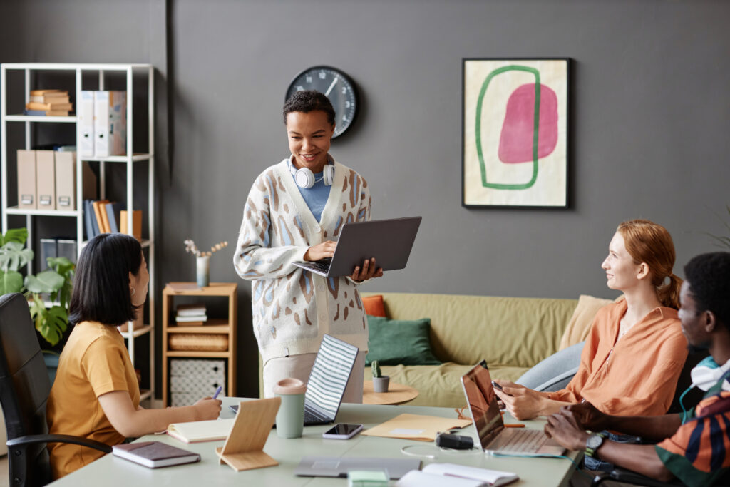 Diverse group of young people in business meeting at table with Black young woman presenting ideas, copy space